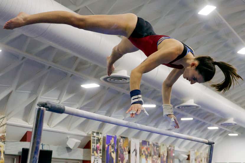 Gymnast Alix Pierce soars through the air on the bars during a practice at Texas Woman’s...
