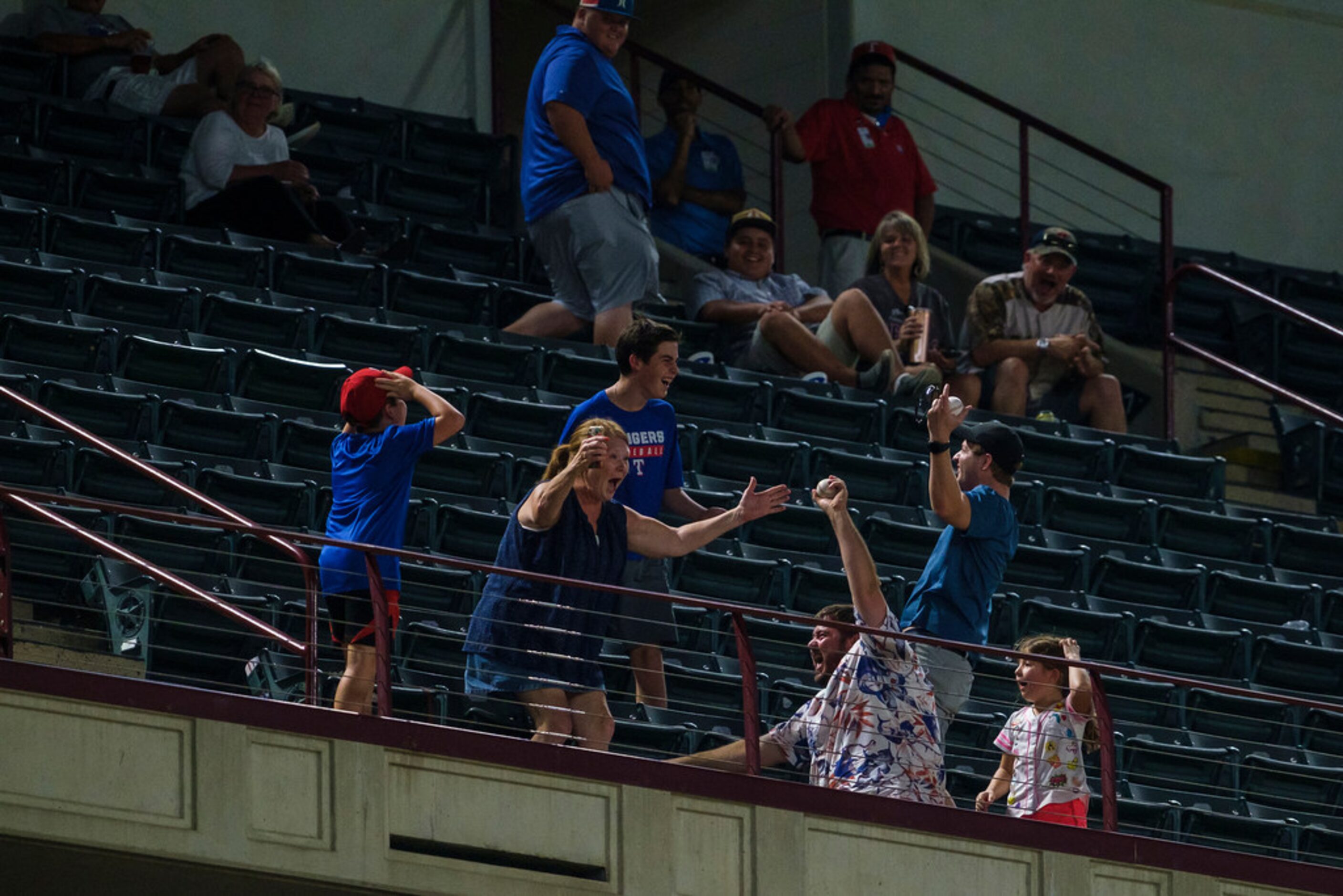 A fan celebrates snagging a foul ball during the seventh inning of a game between the Texas...