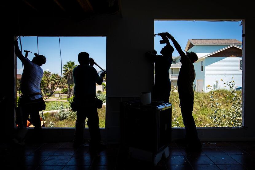 Workers replace windows in early August on a Hurricane Harvey-damaged Port Aransas home...