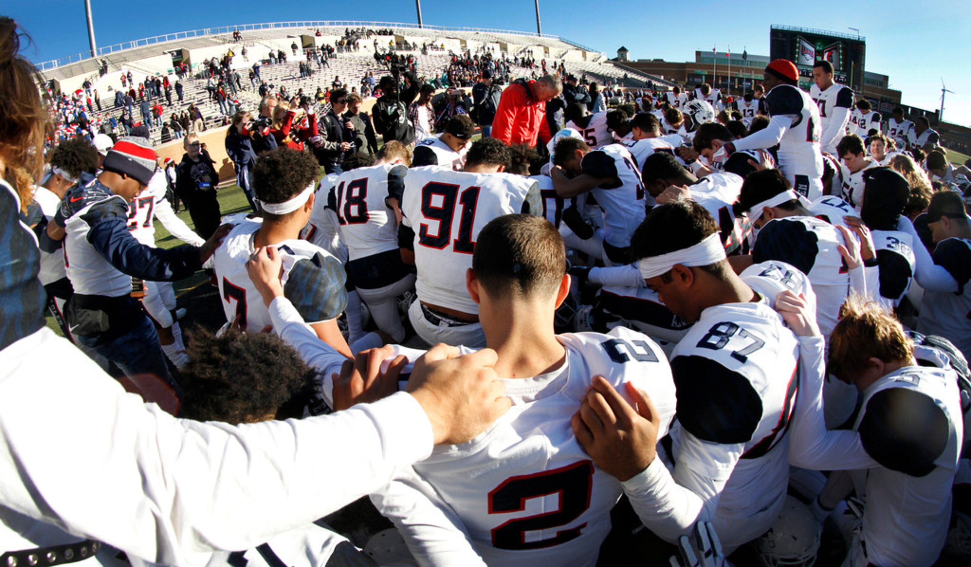 Allen Eagles head coach Terry Gambol joins his players for a prayer at midfield following...