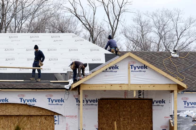 In this Friday, March 21, 2014 photo, roofers install a roof on a new construction home in...