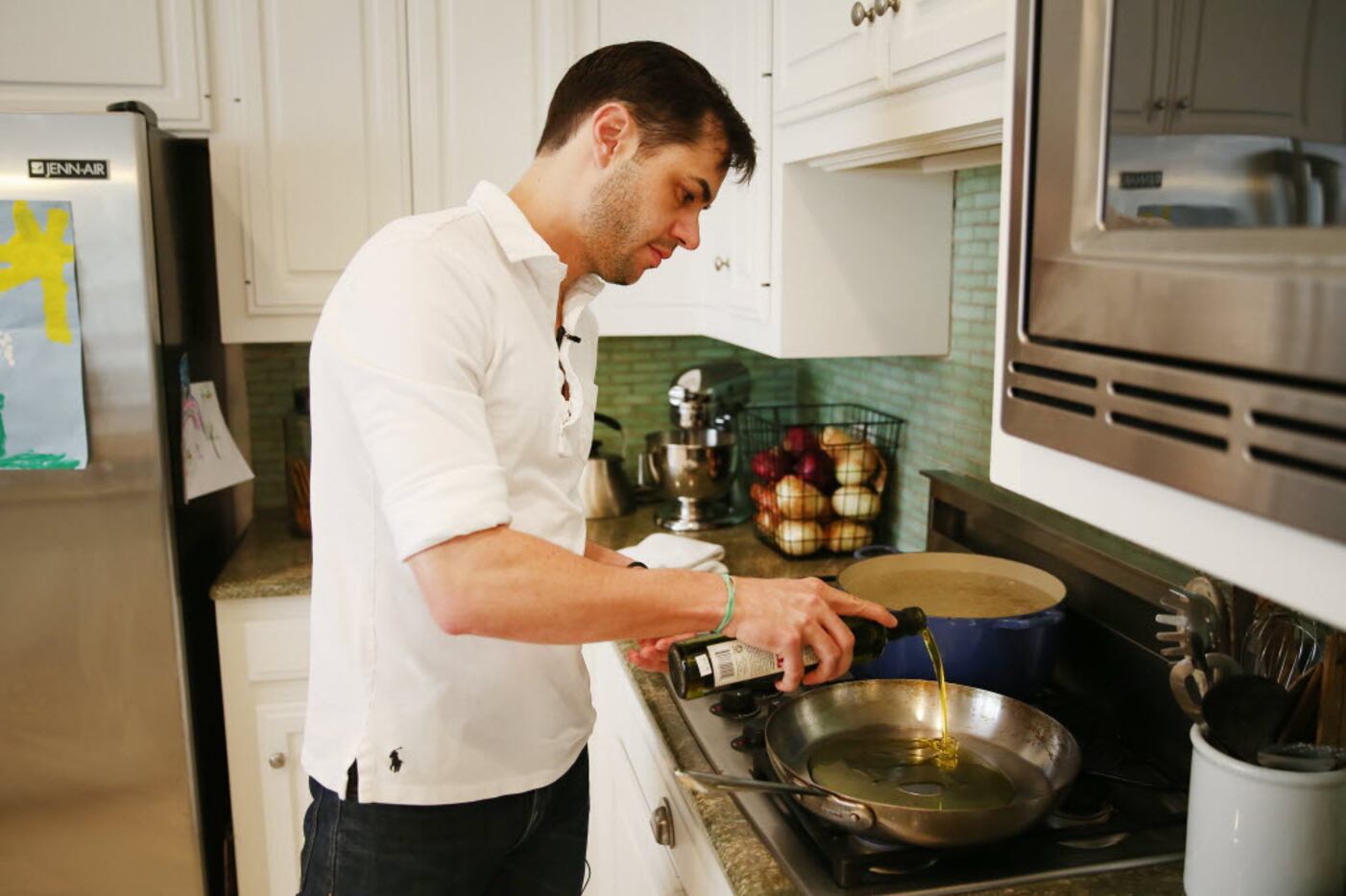 Chef Julian Barsotti adds oil to a pan while cooking a pasta dish at his home in Dallas.