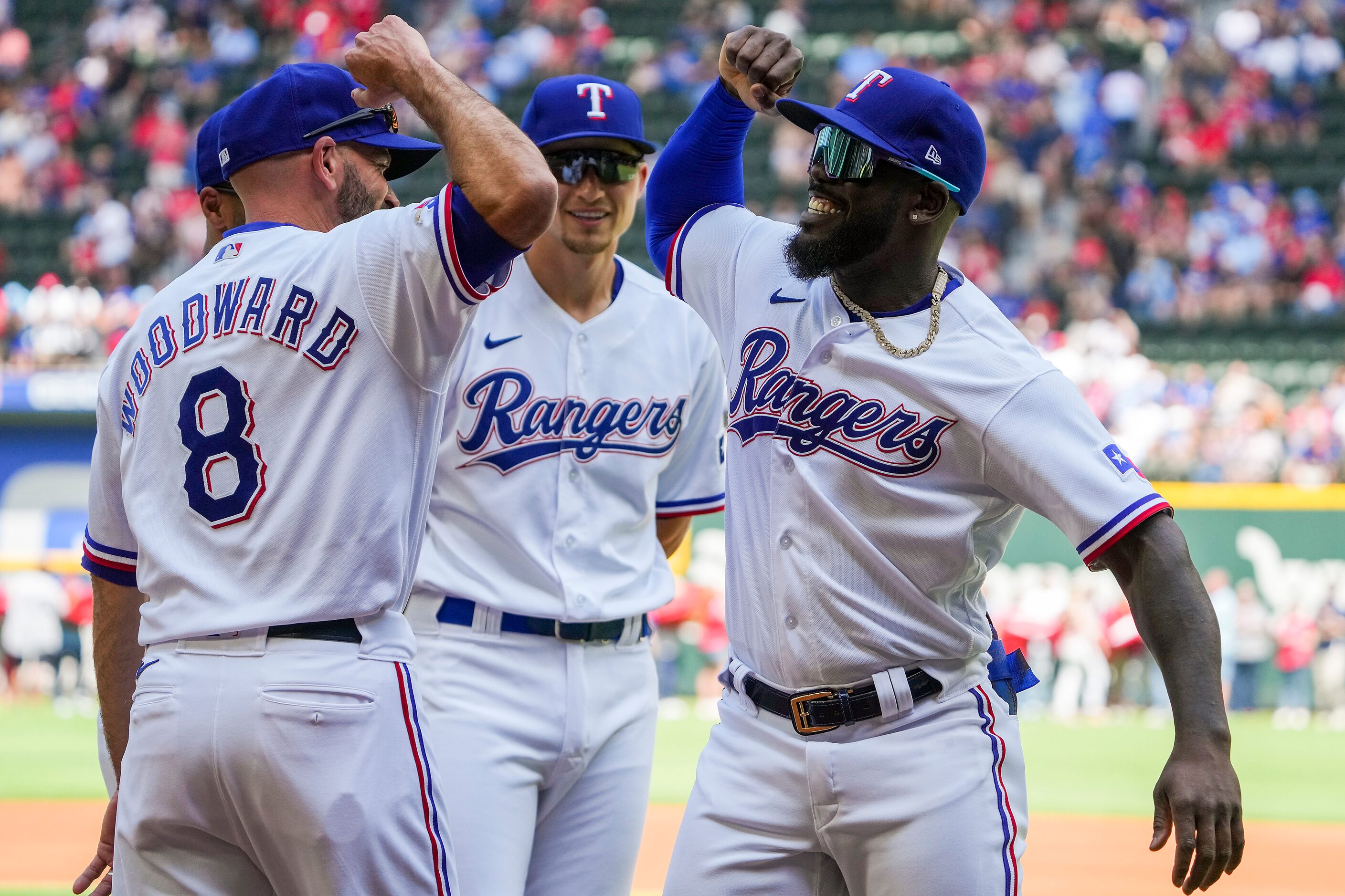 Texas Rangers center fielder Adolis Garcia bumps elbows with Chris Woodward as shortstop...