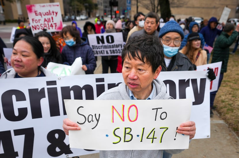 Hank Huang holds a sign reading “Say No To SB-147” as demonstrators march in opposition to...