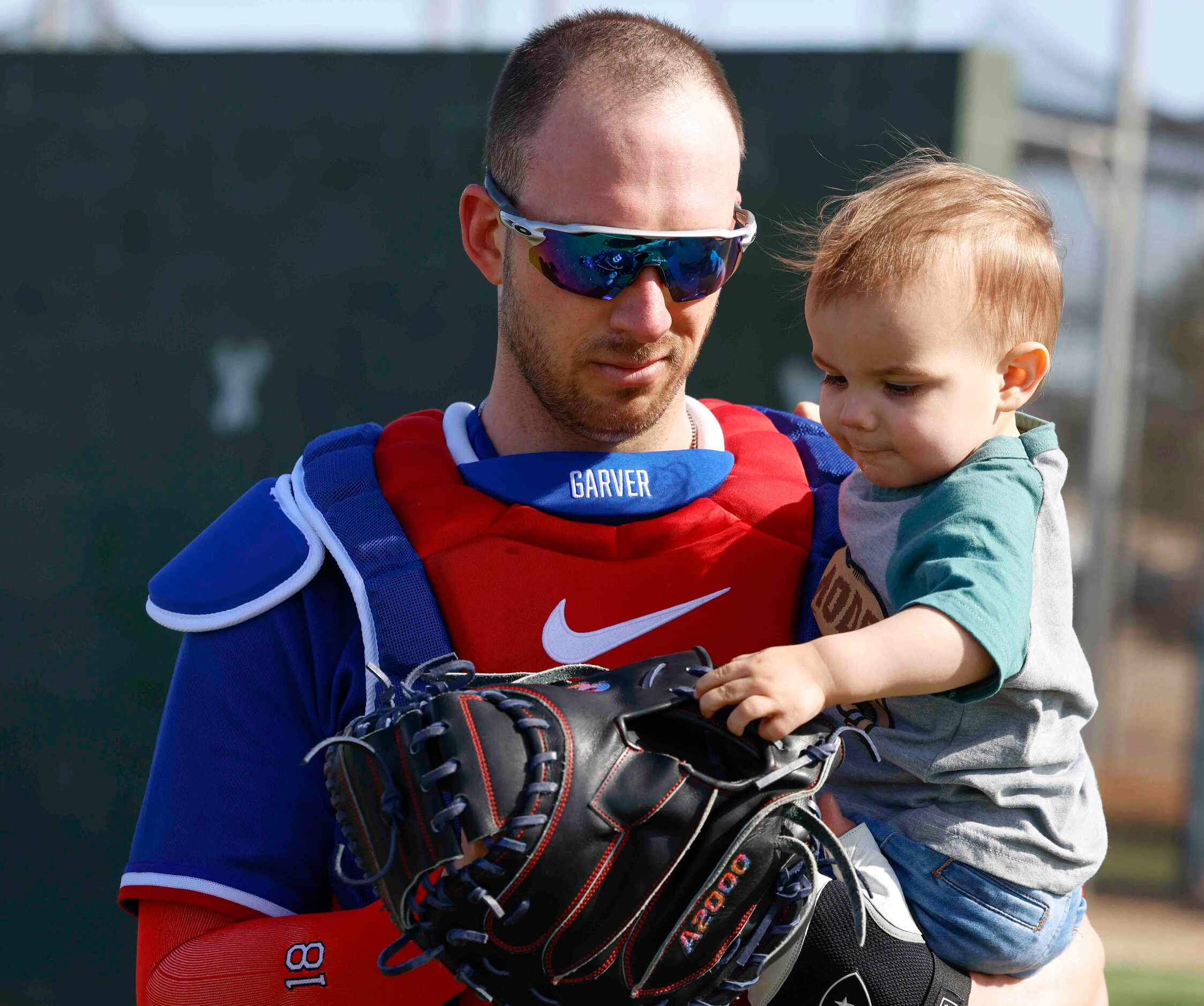 Texas Rangers catcher Mitch Garver lets his 19-month-old son, Gamble, touch his catcher’s...
