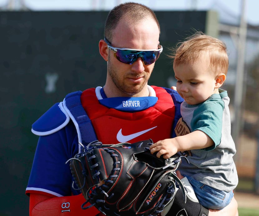 Texas Rangers catcher Mitch Garver lets his 19-month-old son, Gamble, touch his catcher’s...