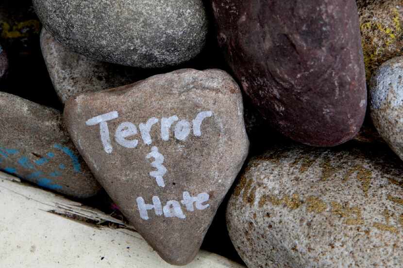 A rock has the words "terror and hate" written on it at an art installation that encourages...