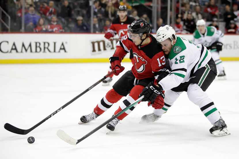 New Jersey Devils center Nico Hischier (13), of Switzerland, competes for the puck with...