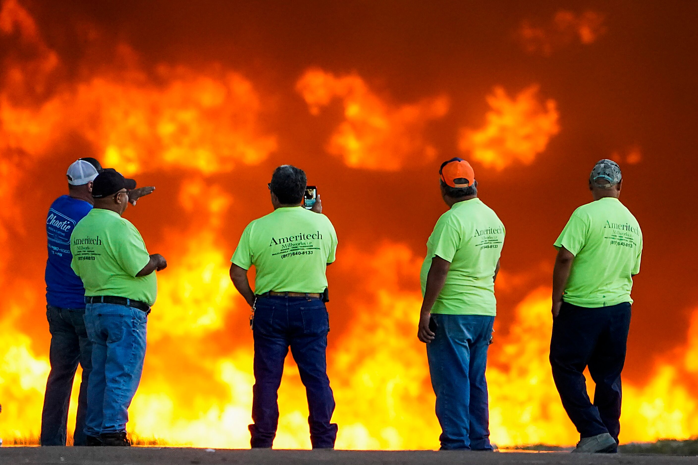 Employees at Ameritech Millworks watch a wall of flames as fire crews battle a massive blaze...