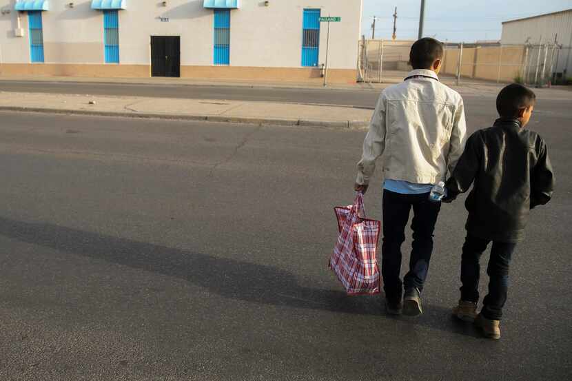 Carlos Joaquín Salinas, de 27 años, y su hijo Salvador de 10 años, cruzan una calle justo...