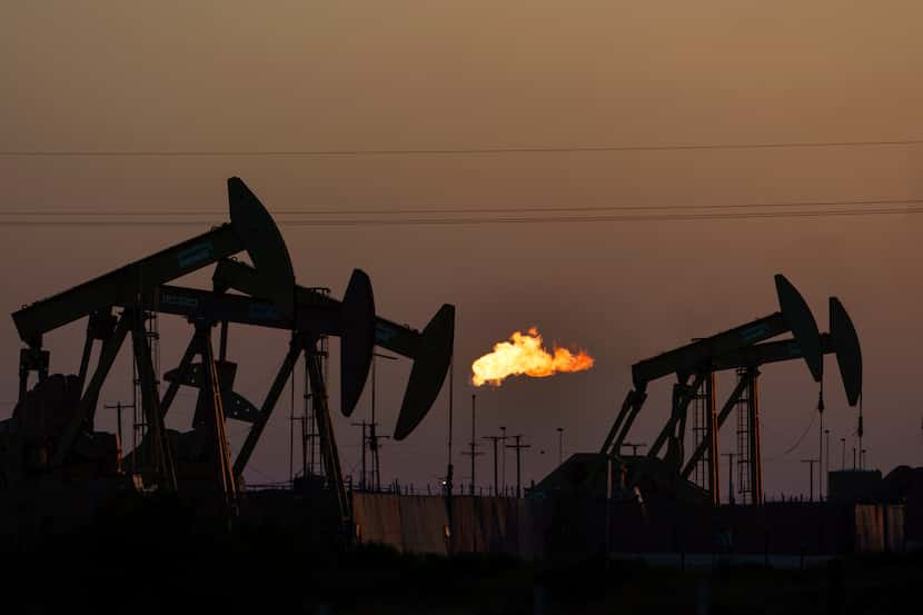 FILE - A flare burns off methane and other hydrocarbons as oil pumpjacks operate in the...