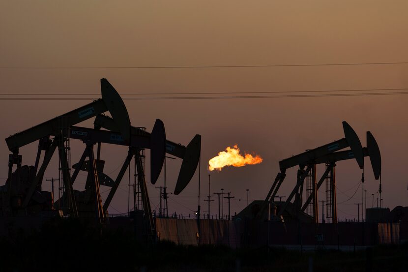 FILE - A flare burns off methane and other hydrocarbons as oil pumpjacks operate in the...