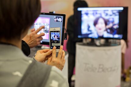 Kahori Aizaki of Fujitsu gets a demo from Shiseido about an app that digitally puts on...