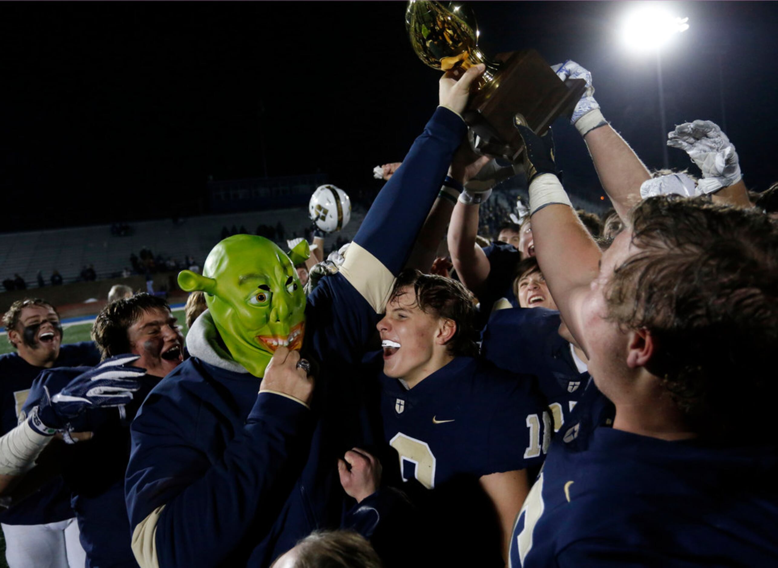 Jesuit coach Brando Hickman wears a Shrek mask and holds up the game trophy as the team...