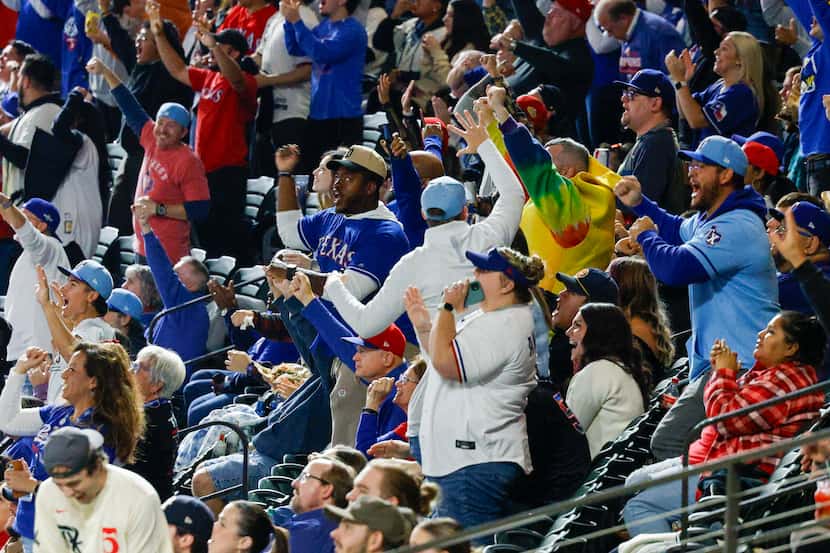 Texas Rangers fans celebrate after the Rangers scored two runs in the second inning during a...