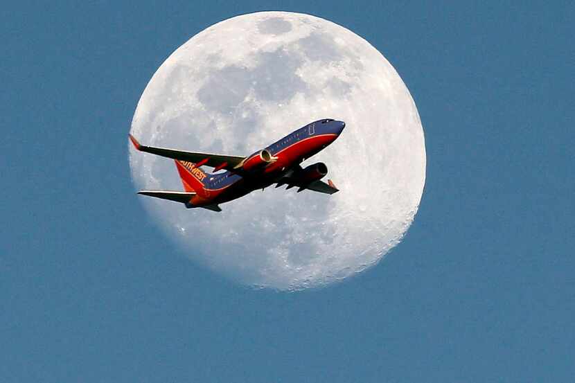  A Southwest Airlines passenger plane crosses the waxing gibbous moon in Whittier, Saturday,...