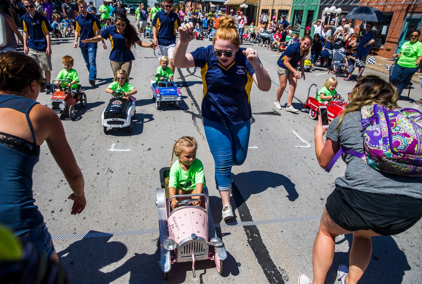 Volunteer Ashlyn Stewart cheers as Ivy Boughton, 3, crosses the finish line first in a...