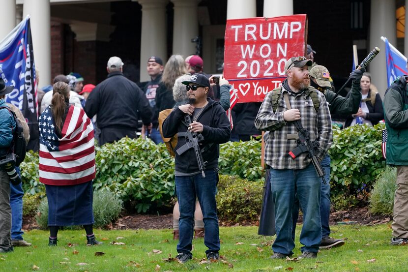 Two men stand armed with guns on Jan. 6, 2021, in front of the Governor's Mansion in...