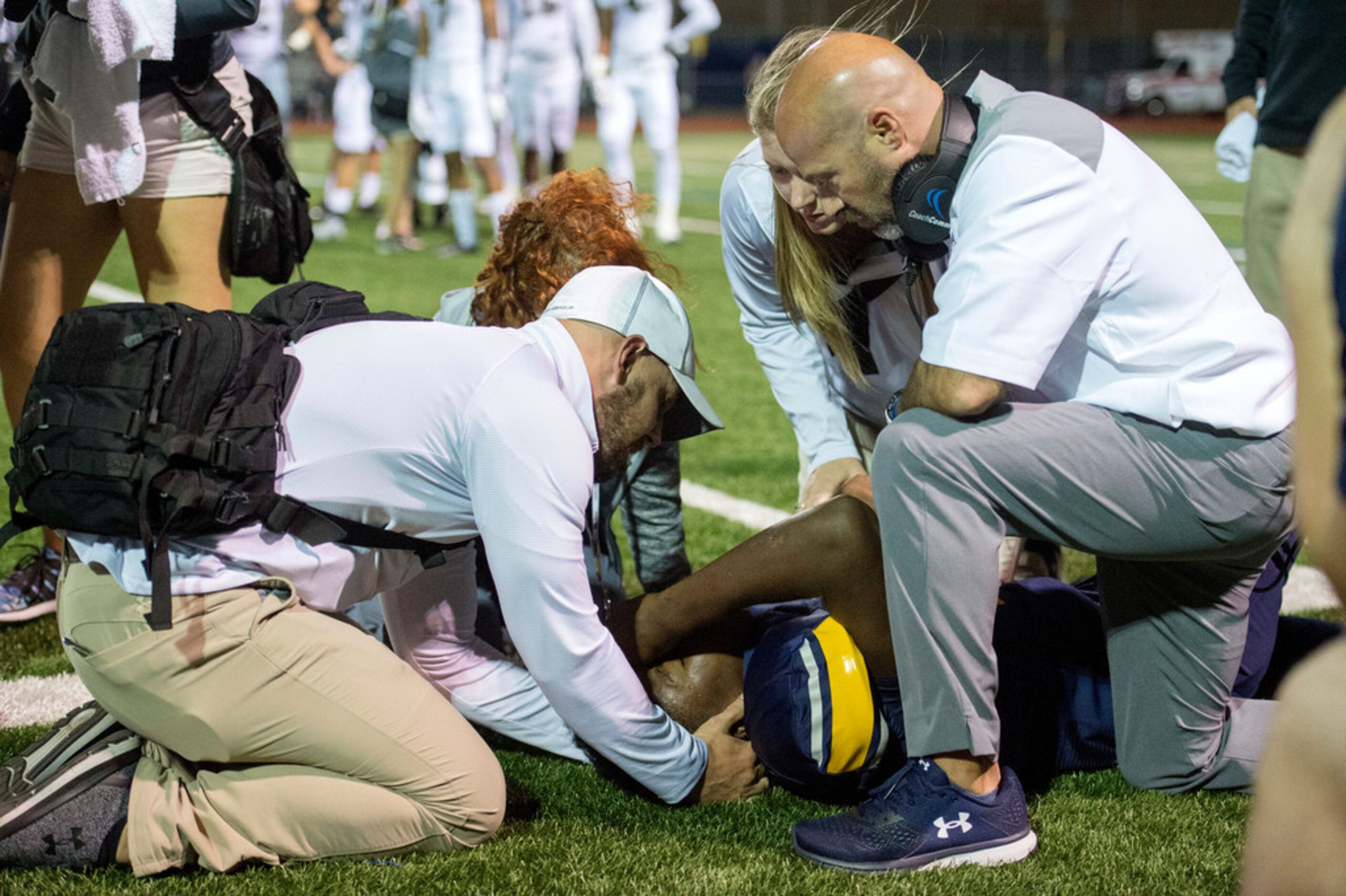 Arlington Lamar head coach Laban Delay (kneeling at right) and members of the training staff...