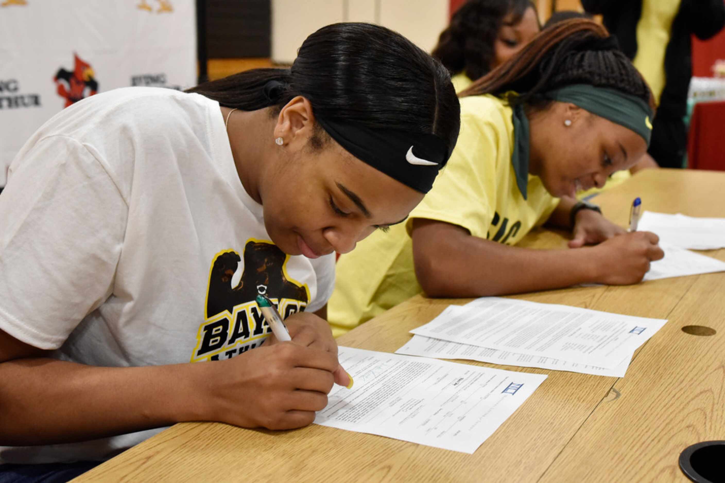 Irving MacArthur girls basketball players Hannah Gusters, left, and Sarah Andrews, sign...