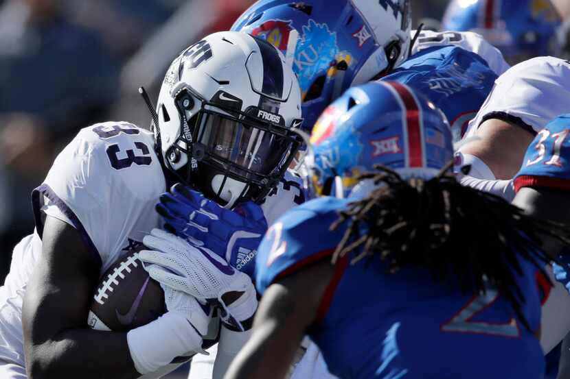 TCU running back Sewo Olonilua (33) is stopped by Kansas defensive tackle J.J. Holmes and...