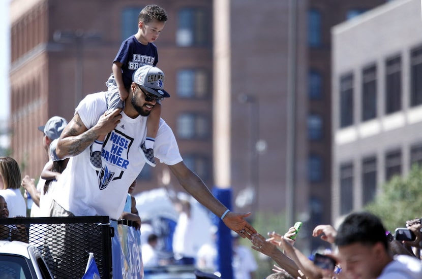 Dallas Mavericks center Tyson Chandler, slaps a fan's hand, as Chandler's son , also named...