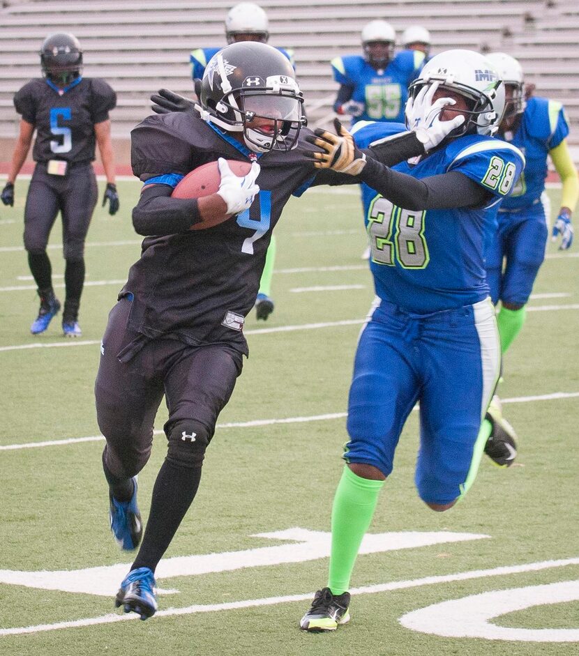 
Tiffany Hill, running back for the Dallas Elite women's football team, stiff-arms Courtney...