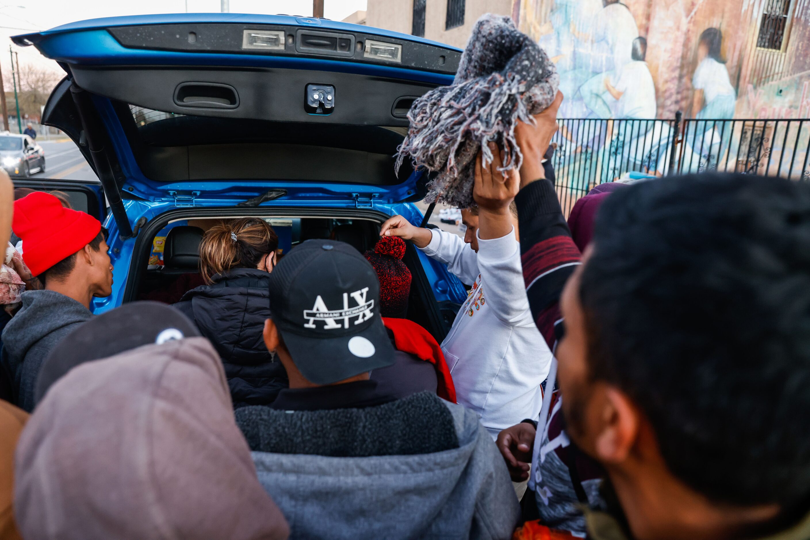 Migrants outside the Centro Pastoral Sagrado Corazon receive aid from local people in El...