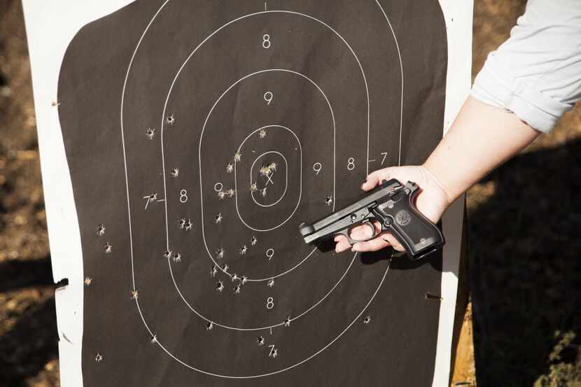 Jenna Duncan holds her gun next to her target at the Quail Creek shooting range on Saturday,...