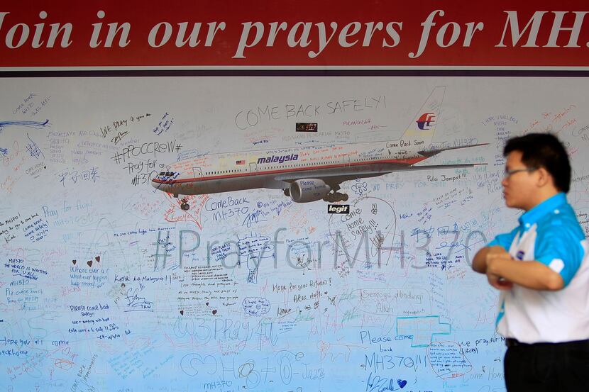 A man walks past a message board for passengers aboard a missing Malaysia Airlines plane at...