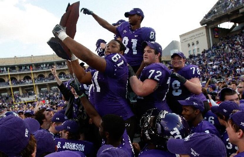 Marcus Cannon #61, Kyle Dooley #72 and Alonzo Adams #81 of the TCU Horned Frogs raise the...