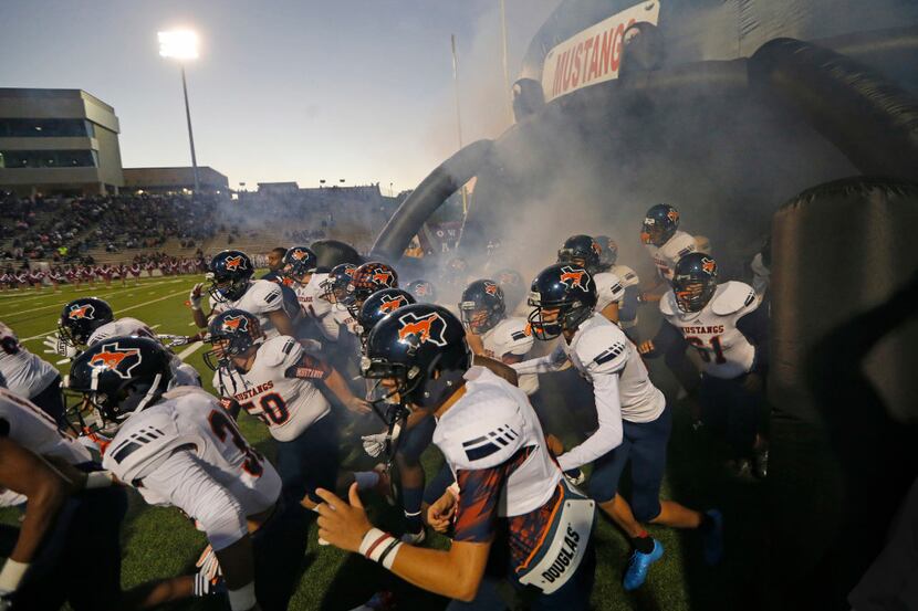 The Sachse Mustangs swarm onto the field before opening kickoff during the Sachse High...