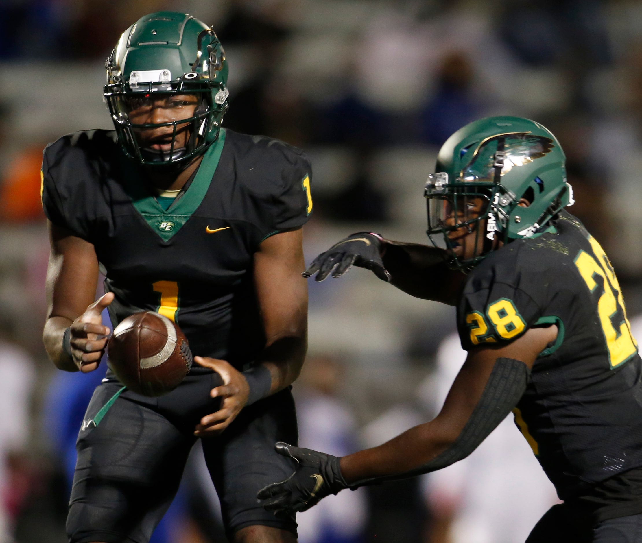 DeSoto running back Eli Williams (28) takes the handoff from quarterback Samari Collier (1)...