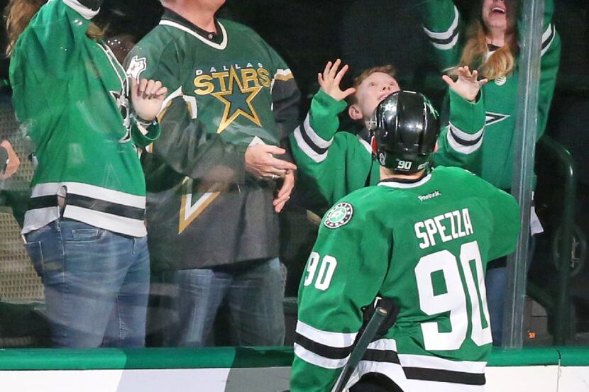 Dallas Stars center Jason Spezza (90) tosses a puck to a young fan after the Stars' 6-1 win...