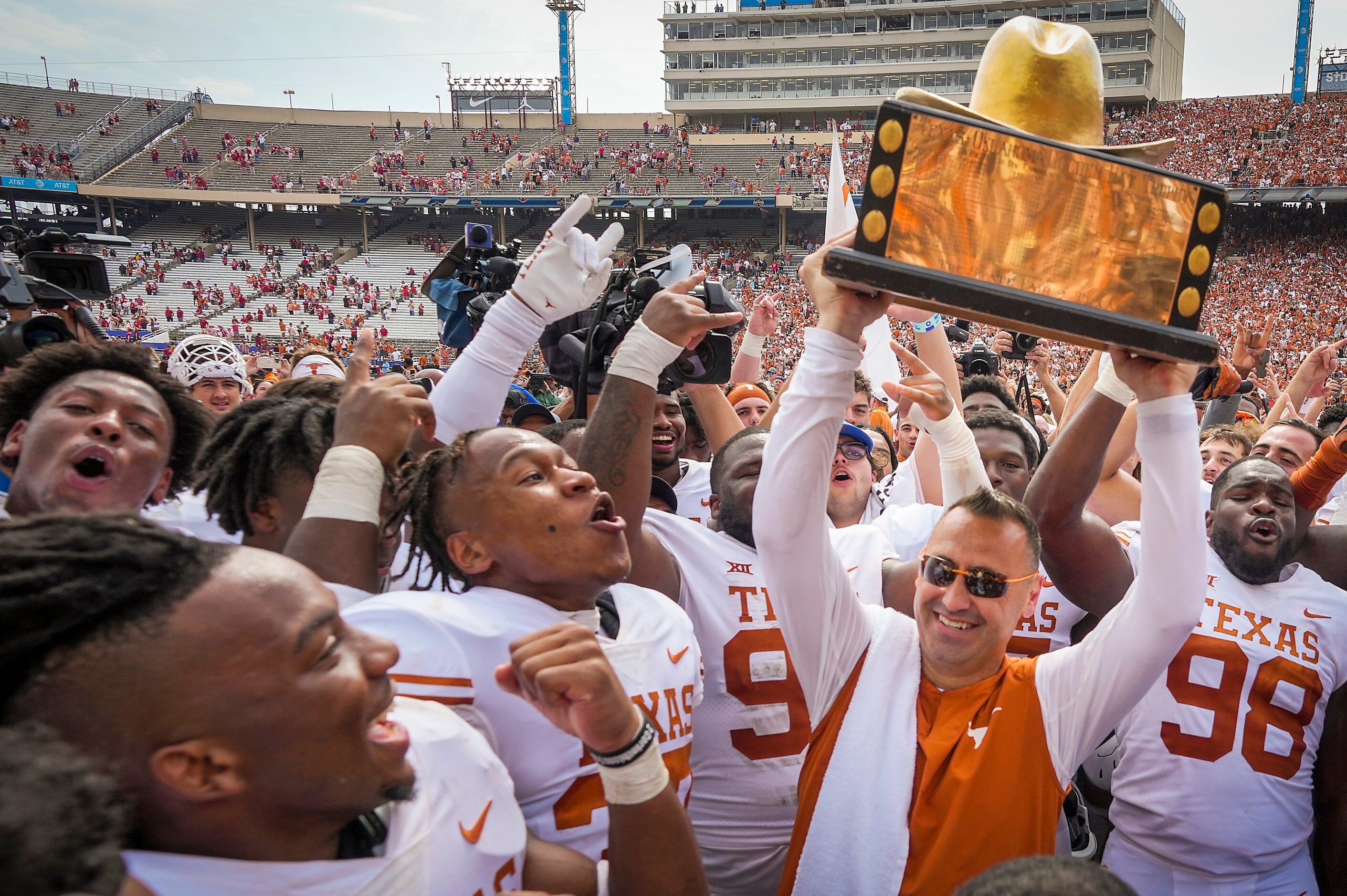 Texas head coach Steve Sarkisian lifts the Golden Hat trophy with his players after a...