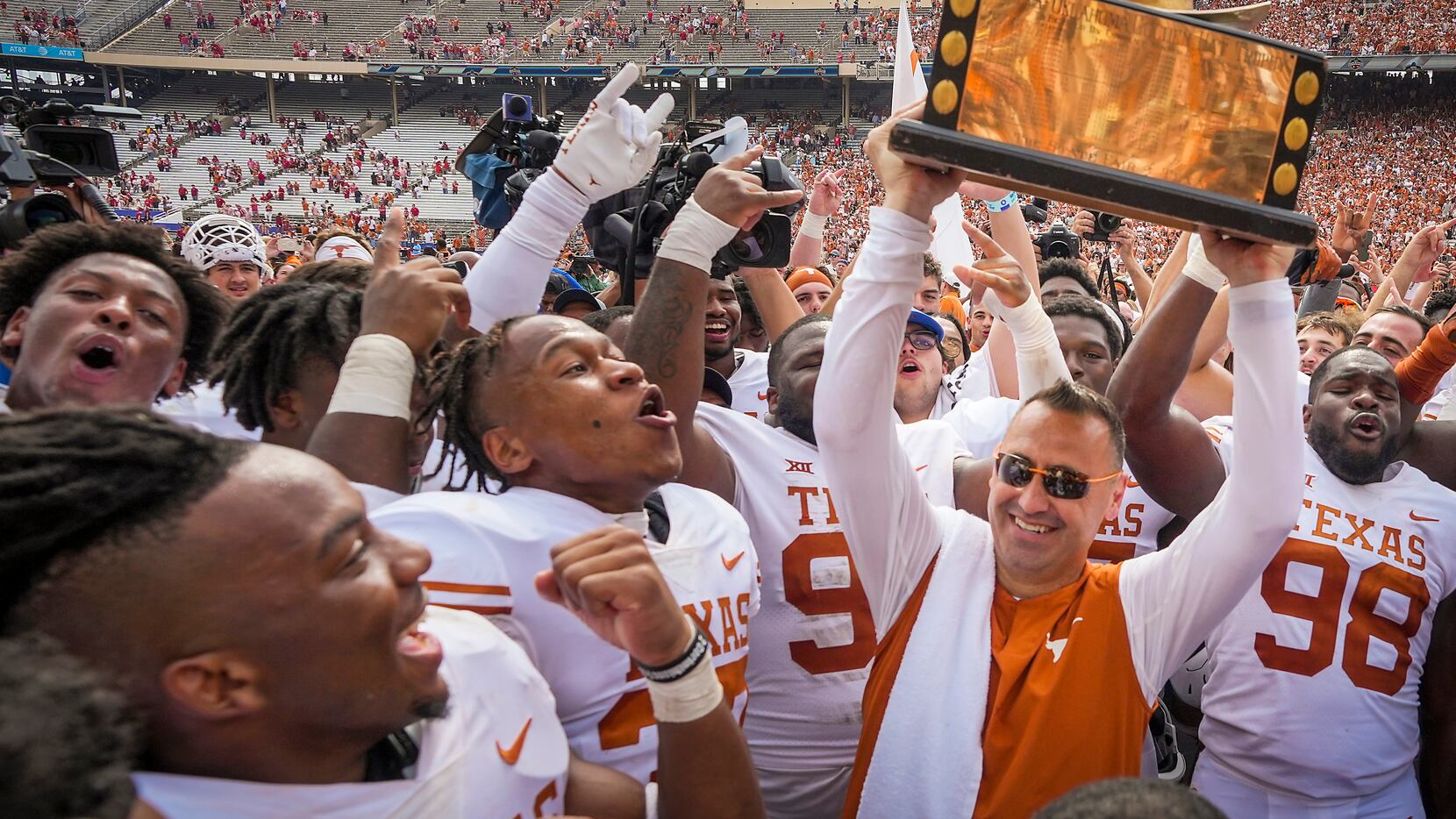 Texas head coach Steve Sarkisian lifts the Golden Hat trophy with his players after a...
