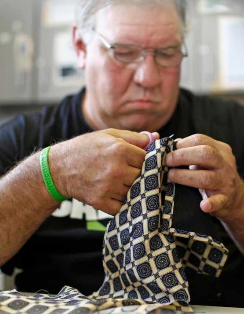 
Charles Piano cuts 
apart ties that he is using to make a quilt during a class at the...