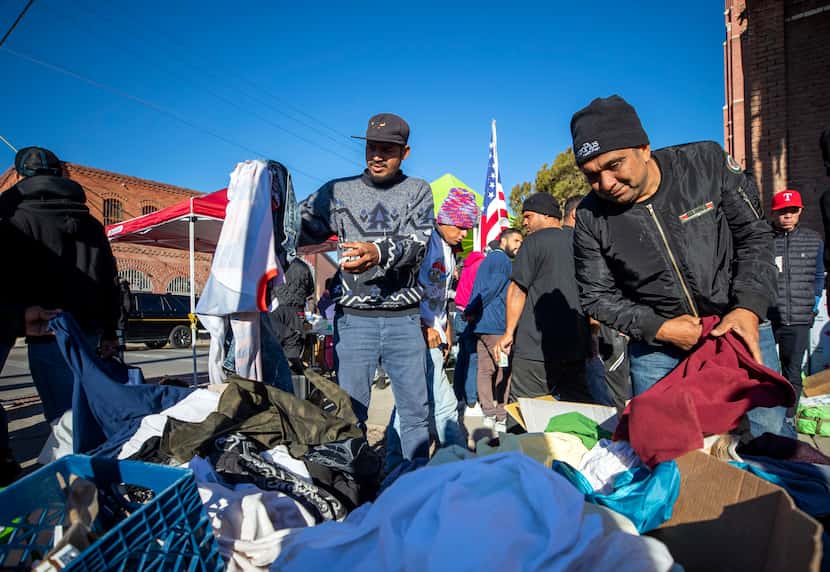 Venezuelan migrant Jose Castillo, right, checks donated clothing at the camping site outside...