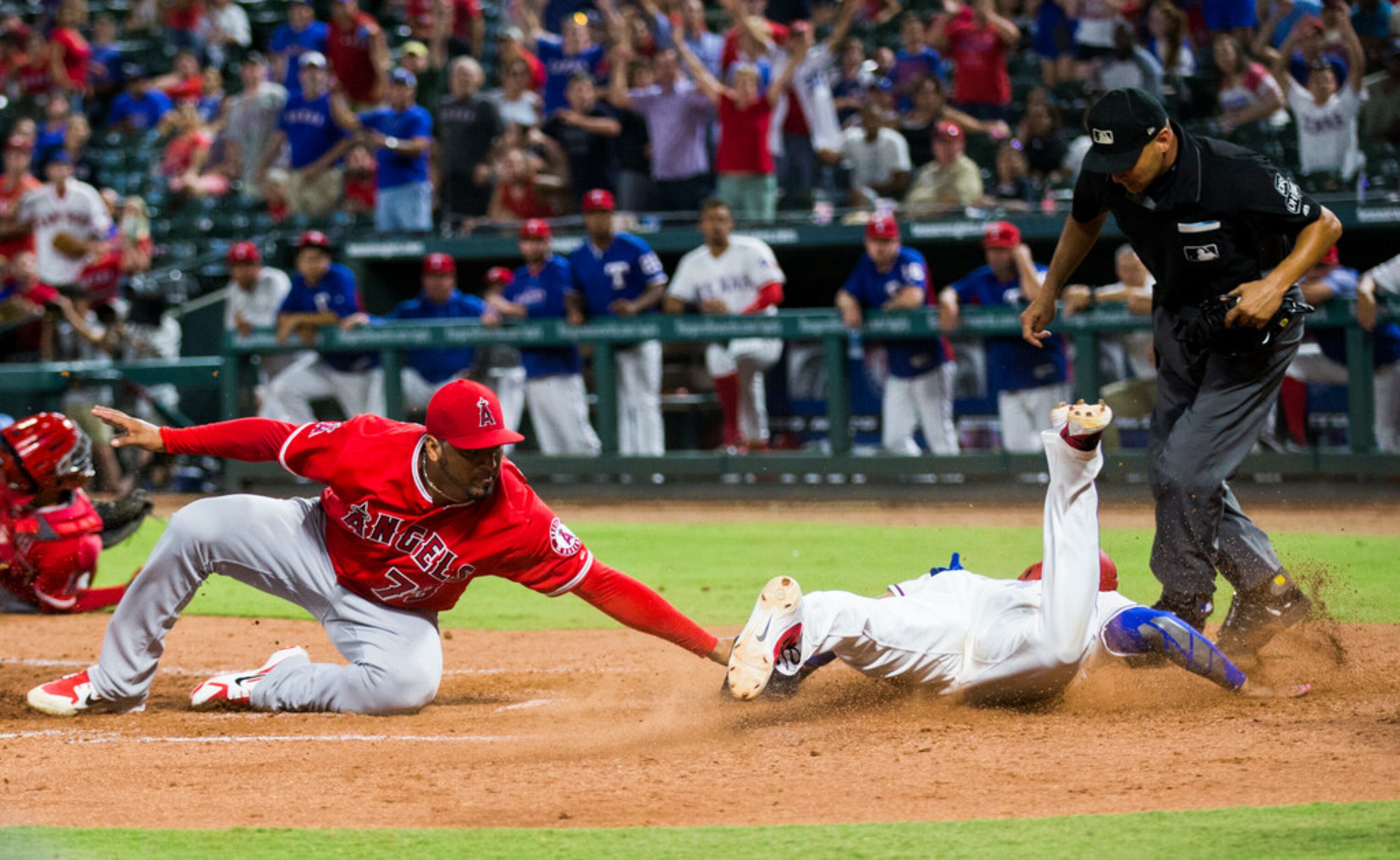 Texas Rangers catcher Robinson Chirinos (61) slides across home plate for a run, narrowly...