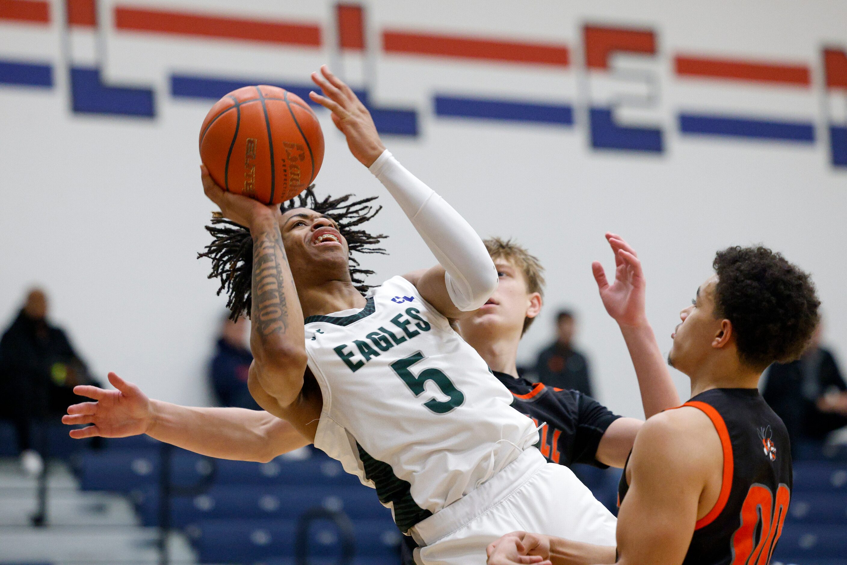 Mansfield Lake Ridge's Ahmare Rose (5) shoots the ball as Rockwall's D'von Turner (right)...