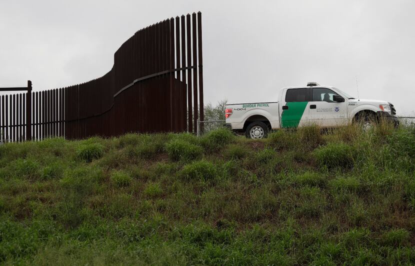 A U.S. Customs and Border Patrol agent passes along a section of border wall in Hidalgo,...