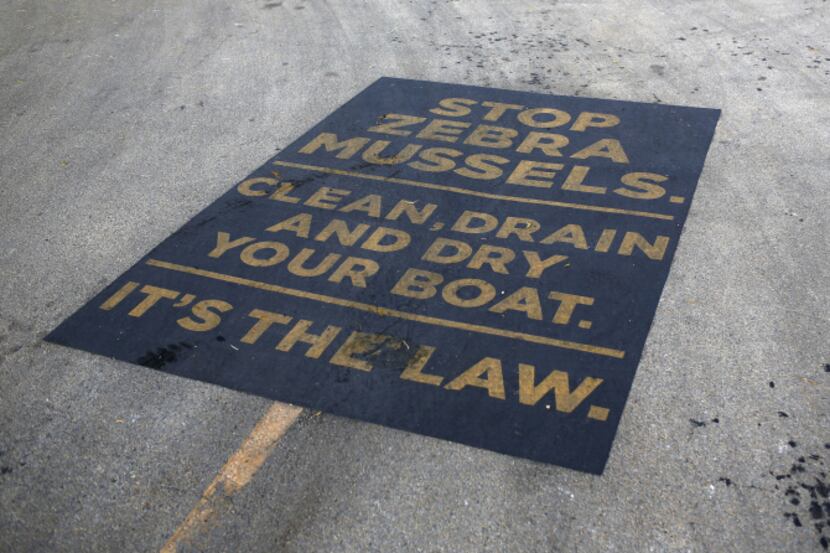 A sign painted on a boat ramp at Arrowhead Park urges boaters at Lewisville Lake to do their...