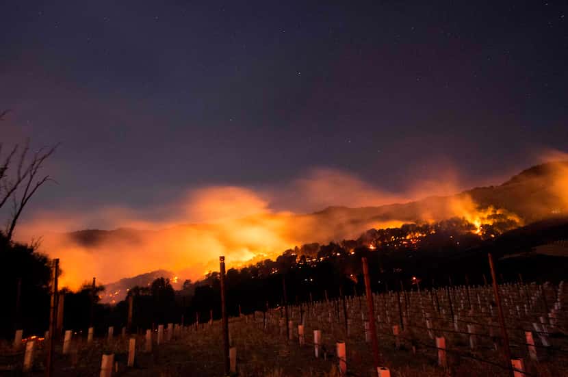 Fire glows on a hillside in Napa, California on October 9, 2017, as multiple wind-driven...