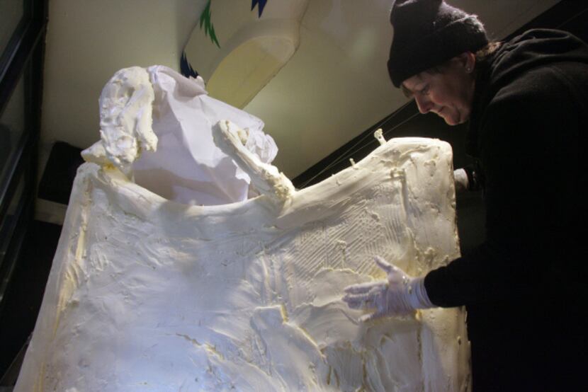 Professional sculptor Sharon BuMann adds a layer of butter to a gondola that is part of the...