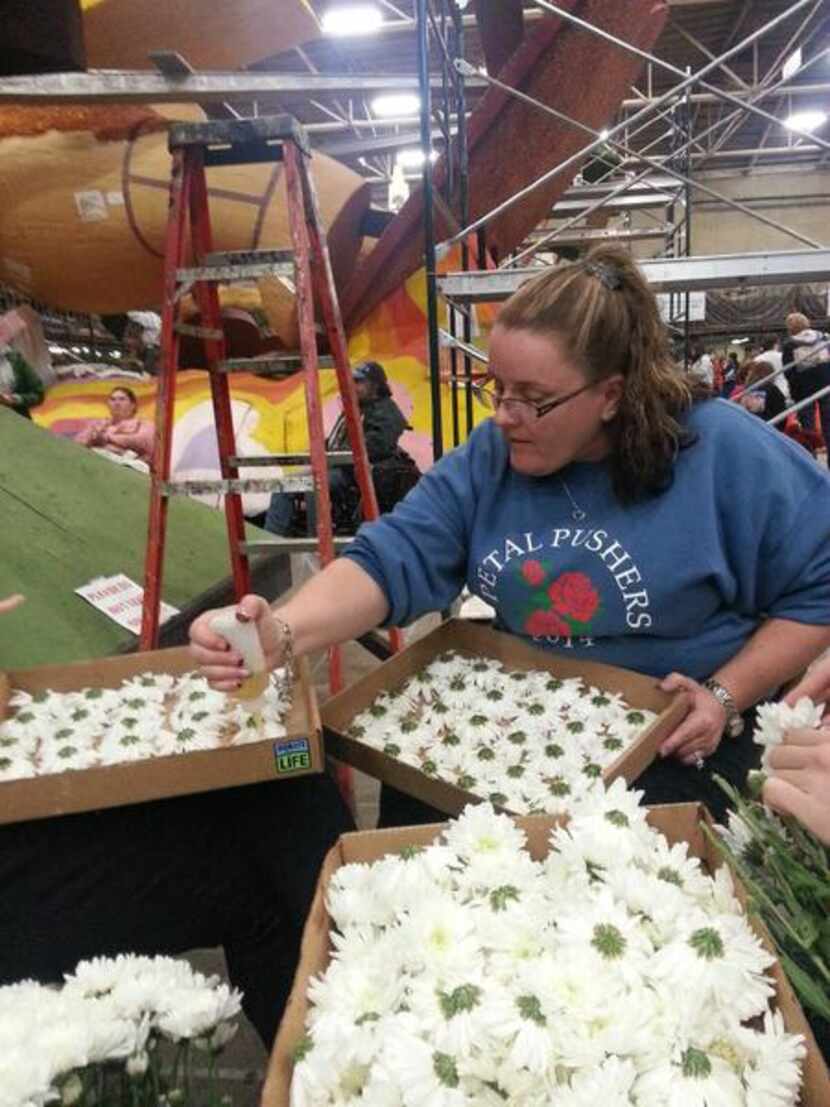 
Teri McAfee applies glue to the flowers before they are affixed to the side of the parade...