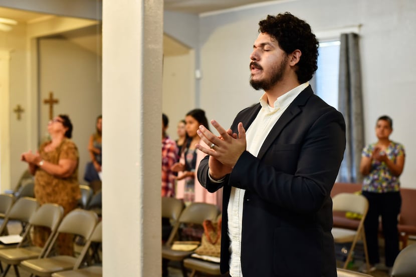 Pastor Juan Ríos, 25, claps his hands while praising during a church service at Iglesia Mi...