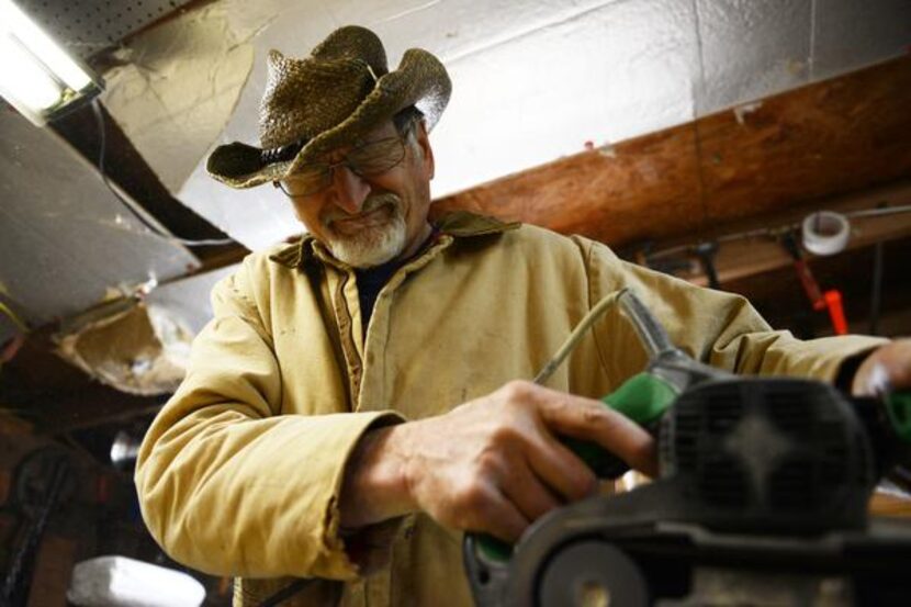 Mayes reacts to sawdust in his eyes while sanding wood for a mission-style chair he is...