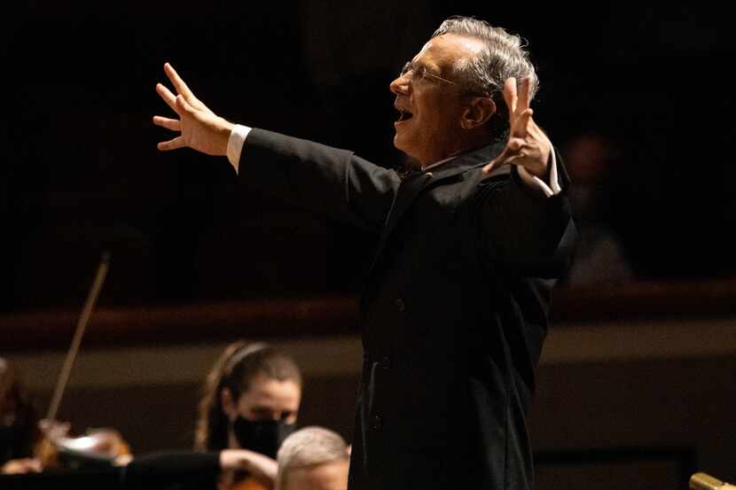 Fabio Luisi leads an orchestra while conducting with his arms out.