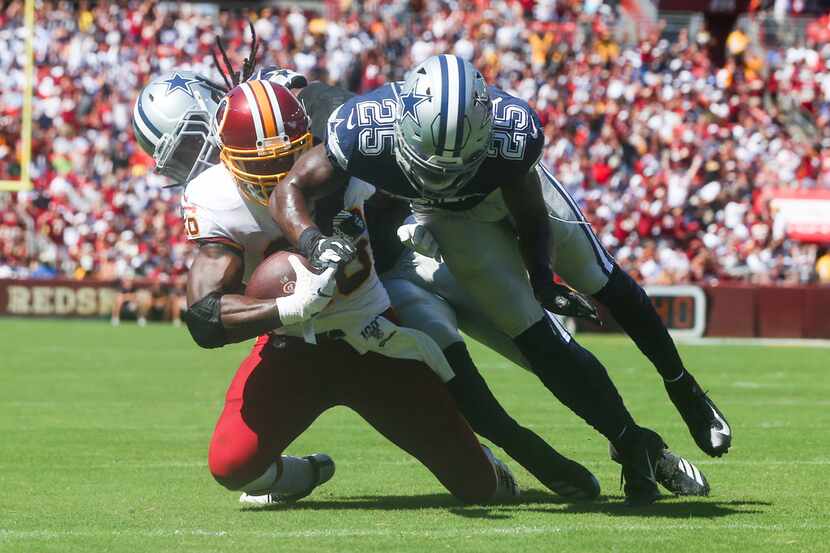 Washington Redskins running back Adrian Peterson (26) carries the ball as he is defend by...