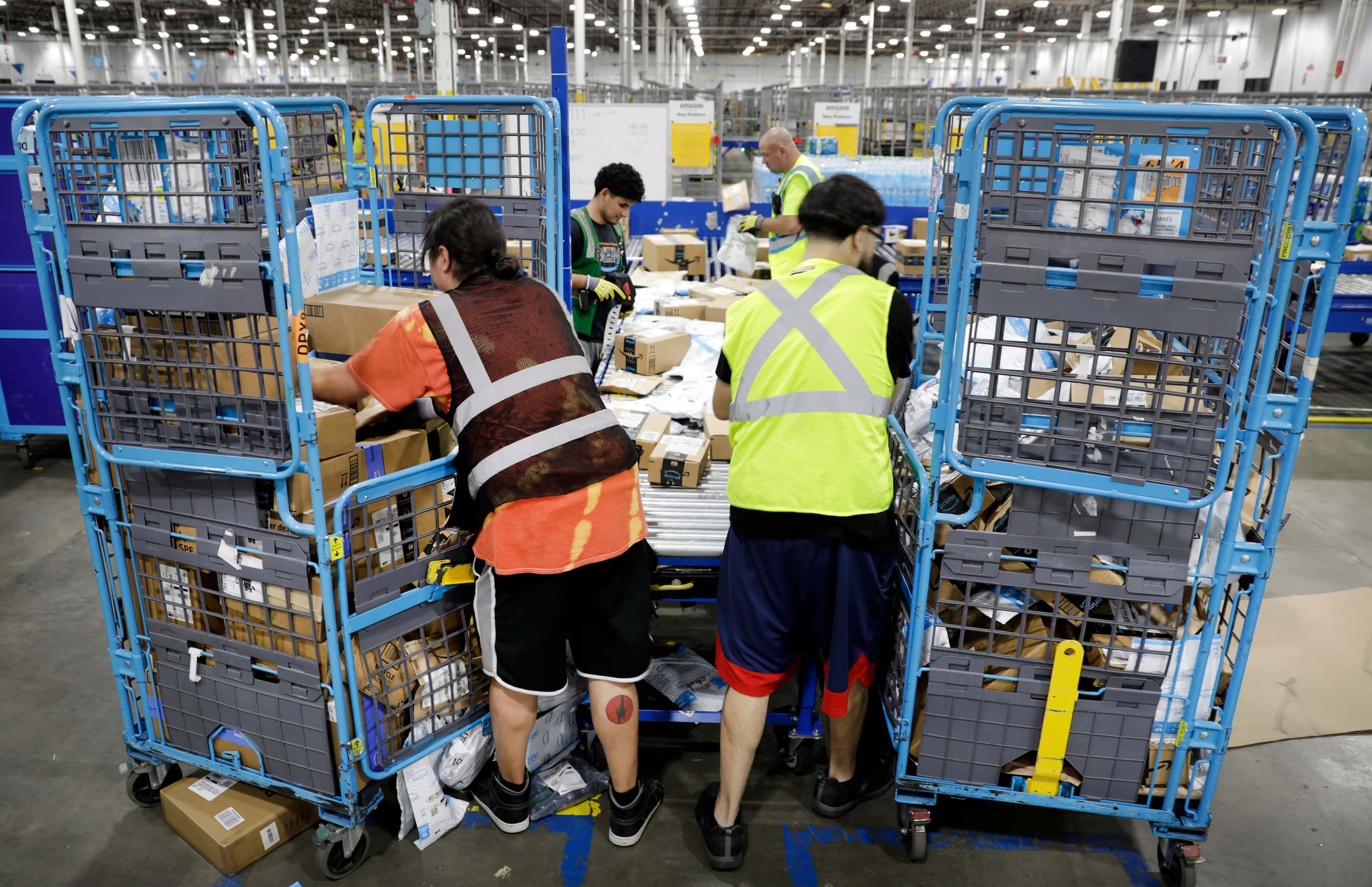 Crew members unload carts of early PRIME day deal packages after they arrived on trucks at...